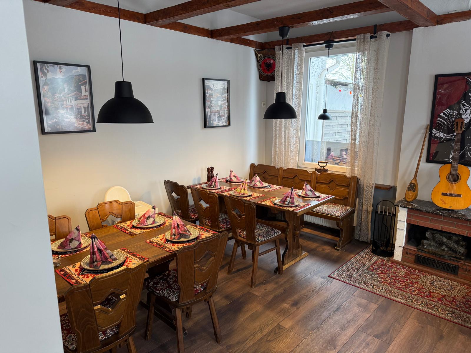 Gemütliche Sitzecke im Troja mit Holzmöbeln, Teppichen und Gitarre an der Wand